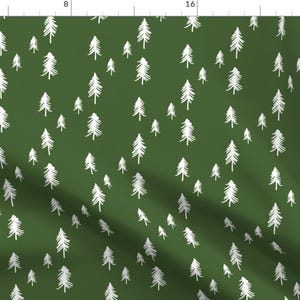May include: A green fabric with a white repeating pattern of stylized pine trees. The fabric is a dark green color and the trees are a light white color.