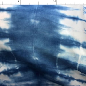 May include: A blue and white tie-dye fabric with a subtle, uneven pattern. The fabric has a soft, flowing texture.