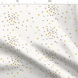 May include: White fabric with a repeating pattern of small, colourful dots. The dots are in shades of grey, pink, and yellow.