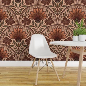 May include: A white molded plastic chair with a curved back and four light wood legs stands before a wall covered in wallpaper featuring a repeating pattern of large orange and brown flowers with dark green leaves on a light peach background.