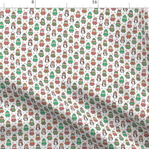 May include: A white fabric with a repeating pattern of penguins wearing different colored hats and scarves. The penguins are arranged in rows and columns, and the background is white.