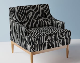 May include: A black and white patterned armchair with wooden legs. The chair has a curved back and a wide seat.