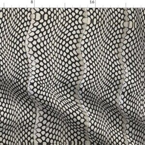 Può includere: Un tessuto con motivo a pelle di serpente bianco e nero con un design a onde sottile. Il tessuto è testurizzato e ha una leggera lucentezza iridescente.