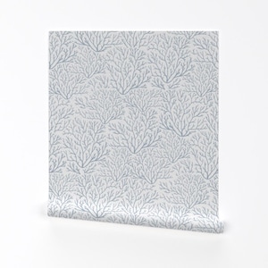 May include: A roll of wallpaper featuring a repeating pattern of stylized, light blue tree branch designs on a light gray background. The branches have a delicate, organic appearance, creating a subtle, textured effect. The wallpaper is partially unrolled, revealing the pattern.