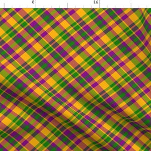 May include: A fabric with a plaid pattern in shades of gold, green, purple, and gray. The diagonal lines create a dynamic visual effect. The fabric is likely used for clothing or home decor.