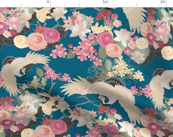 Puede incluir: Una tela azul turquesa con un patrón repetitivo de grullas blancas, flores rosas y blancas y detalles dorados. El diseño está inspirado en el arte tradicional japonés.