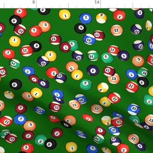 May include: A green felt pool table with a variety of billiard balls scattered across the surface. The balls are numbered 1 through 15, and include the solid, striped, and cue ball.