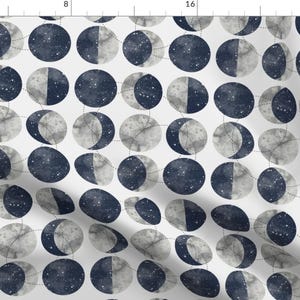 May include: A white fabric with a repeating pattern of blue and gray moon phases. Each moon phase is surrounded by a dotted circle.