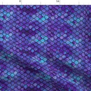 May include: A fabric featuring a repeating pattern of overlapping diamond-shaped scales in shades of deep purple, violet, and bright cyan blue. The surface has a textured appearance with light and dark gradients creating a sense of depth.