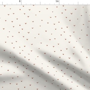 May include: A white fabric with a repeating pattern of small, hand-drawn brown hearts.