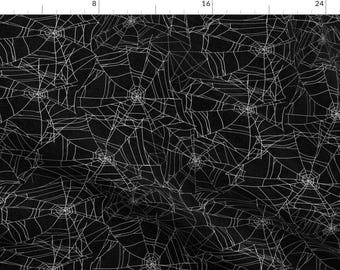May include: Black fabric with a white spiderweb pattern. The web pattern is a repeating design of spiderwebs.