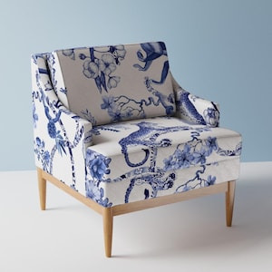 Può includere: Una poltrona bianca con un motivo floreale blu e bianco con scimmie, leopardi e fiori. La poltrona ha gambe in legno.