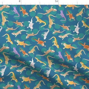 May include: A teal blue fabric with a repeating pattern of colorful lizards on a teal blue background with white and teal blue polka dots.