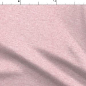 May include: A close-up of a pale pink fabric with a subtle textured weave. The fabric has a soft, slightly wrinkled appearance.