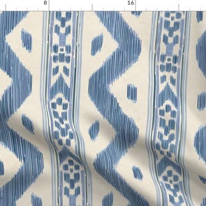 Puede incluir: Tela color crema con un patrón repetitivo de zigzags y rayas verticales azules. El diseño tiene una apariencia texturizada dibujada a mano, con los elementos azules que se asemejan a pinceladas. Adecuado para la decoración del hogar y proyectos de manualidades.