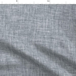 May include: A close-up of a gray textured fabric with a subtle woven pattern. The fabric has a slightly wrinkled appearance, giving it a casual and relaxed look.