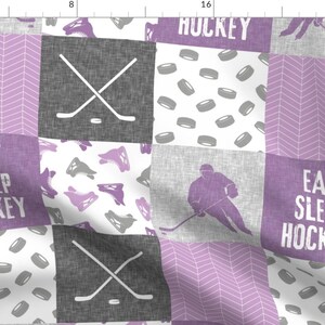 May include: A purple and gray patchwork fabric with a hockey theme. The fabric features hockey sticks, pucks, skates, and the text "Eat Sleep Hockey" and "Huckey".