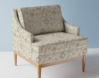 May include: A beige armchair with a floral pattern in shades of green. The chair has a wooden frame and legs. The design features a high back and armrests, offering a comfortable seating option for a living room or bedroom.