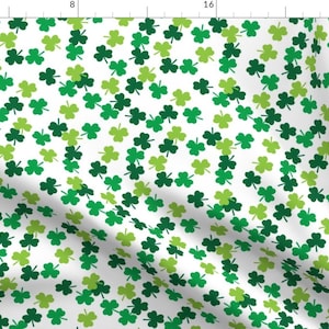 May include: White fabric with a repeating pattern of green shamrocks in varying shades. The shamrocks are scattered across the surface, creating a festive and cheerful design. Ideal for St. Patrick's Day or Irish-themed projects.