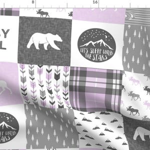 May include: A patchwork fabric design with a gray and white color scheme. The fabric features a variety of patterns, including plaid, arrows, and woodland animals. The text "BABY GIRL" and "LET'S SLEEP UNDER THE STARS" is included in the design.