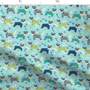 May include: A seamless pattern featuring miniature schnauzers wearing pajamas in various colors and patterns. The dogs are on a light blue background with white bones and green tennis balls.