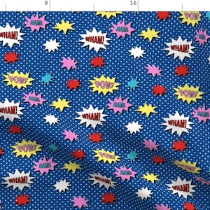 May include: A blue fabric with a white polka dot pattern. The fabric features a repeating pattern of colorful comic book sound effects like "BAM", "POW", and "WHAM!" in white letters with red outlines.