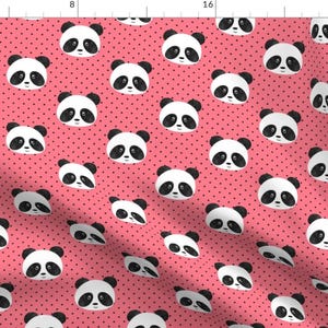 May include: A pink fabric with a repeating pattern of black and white panda faces on a pink background with small black polka dots.
