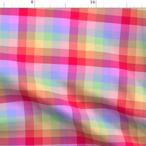 May include: A colorful plaid fabric with a rainbow pattern in shades of pink, red, orange, yellow, green, blue, and purple. The fabric is woven in a checkered pattern with alternating colors.