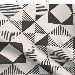 May include: Cream-coloured fabric with a repeating geometric pattern. The design features black shapes, including triangles, squares, and diamonds, with textured, hand-drawn lines. The overall aesthetic is modern and abstract.