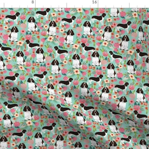 May include: A seamless pattern featuring a cute Springer Spaniel dog breed with brown and white fur, surrounded by pink, white, and green flowers on a turquoise background.