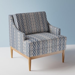 May include: A blue and white patterned armchair with a wooden frame and legs. The chair has a geometric design with a light blue background and dark blue accents.