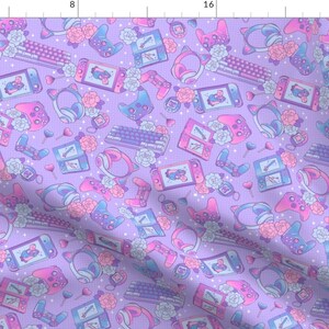 May include: A purple fabric with a repeating pattern of pink and blue gaming accessories, including controllers, headphones, and a handheld gaming console. The pattern also includes flowers and stars.