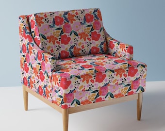 May include: A floral patterned armchair with a light wood frame and legs. The upholstery features a vibrant mix of red, pink, orange, and yellow flowers on a cream background. The chair has a high back and armrests.