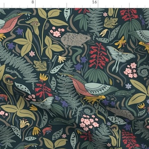 May include: A fabric pattern with a dark teal backdrop, showcasing a repeating design of birds, moths, frogs, and diverse plants. The birds have pink and yellow details, and the moths are light blue. The plants include ferns, flowers, and other foliage.