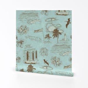 May include: A light blue wallpaper with a repeating pattern of brown illustrations. The illustrations include palm trees, a lighthouse, a car, a building, birds, and flowers. The wallpaper has a subtle textured look.