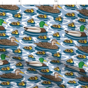 Peut inclure: Un motif de tissu bleu et blanc avec un motif répété de canards et de canetons nageant dans un étang. Les canards sont bruns et verts avec des becs jaunes et les canetons sont jaunes.