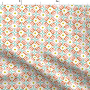 Op de afbeelding: Een herhalend patroon van roze, turquoise en gele bloemen op een witte achtergrond. Het patroon is geometrisch en creëert een modern en stijlvol ontwerp.