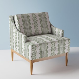 Puede incluir: Un sillón con estampado verde y blanco con marco y patas de madera. El sillón tiene un respaldo alto y un reposabrazos curvo.
