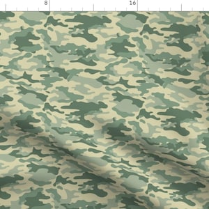 May include: A camouflage pattern fabric with shades of green and beige. The fabric has a slightly textured surface.