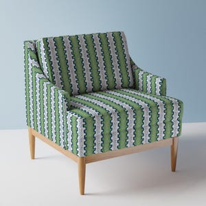 Könnte beinhalten: Ein grün-weiß gestreifter Sessel mit geometrischem Muster. Der Sessel hat Holzbeine und einen bequemen, gepolsterten Sitz.