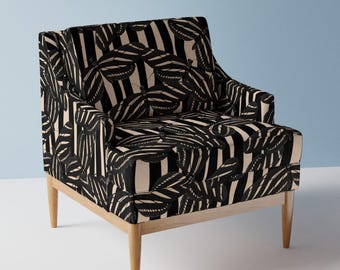 May include: A black and white armchair with a butterfly and stripe pattern. The chair has wooden legs.