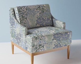 May include: A floral patterned armchair with a light blue and green design. The chair has a wooden frame and legs.