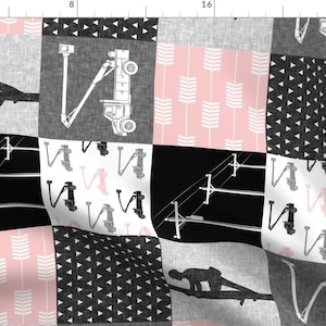 May include: A black and white patchwork fabric with pink accents. The fabric features a variety of patterns, including arrows, triangles, and a crane.