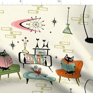 Può includere: Tessuto in stile moderno della metà del secolo con gatti neri che leggono libri in poltrona. Il design include una scena di soggiorno retrò con scoppi di stelle, forme atomiche e una tavolozza di colori crema, rosa, arancione e verde.