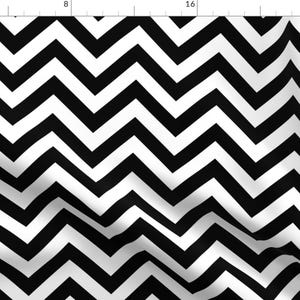 Pode incluir: Tecido com padrão chevron preto e branco. O padrão é composto por ziguezagues pretos e brancos alternados.