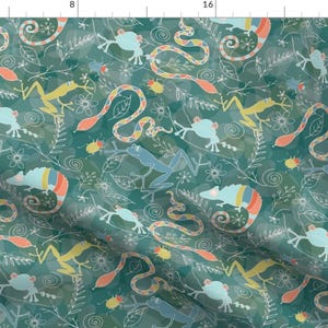 May include: Teal fabric with a repeating pattern of colorful snakes, frogs, and flowers. The design is whimsical and playful, perfect for a child's room or a nature-themed project.