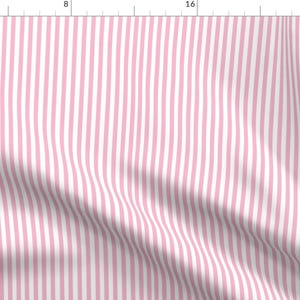 May include: A fabric with a pink and white striped design. The pattern consists of vertical stripes in alternating shades of pink and white. The fabric has a subtle texture, with gentle folds and shadows.