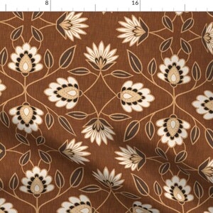 May include: A brown fabric with a repeating pattern of white flowers with brown centers and brown leaves. The fabric has a subtle texture.