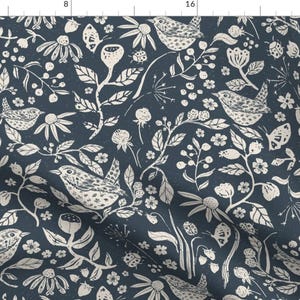 Pode incluir: Um tecido azul marinho com um padrão branco repetitivo de pássaros, flores e folhas. O padrão é um design caprichoso e encantador.