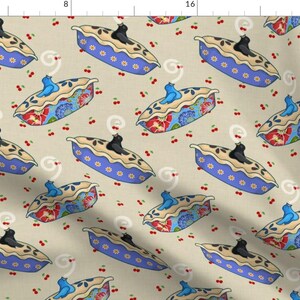 May include: A beige fabric with a repeating pattern of blue and white pie dishes with black birds on top. Each pie dish has a floral design and is surrounded by small red cherries.